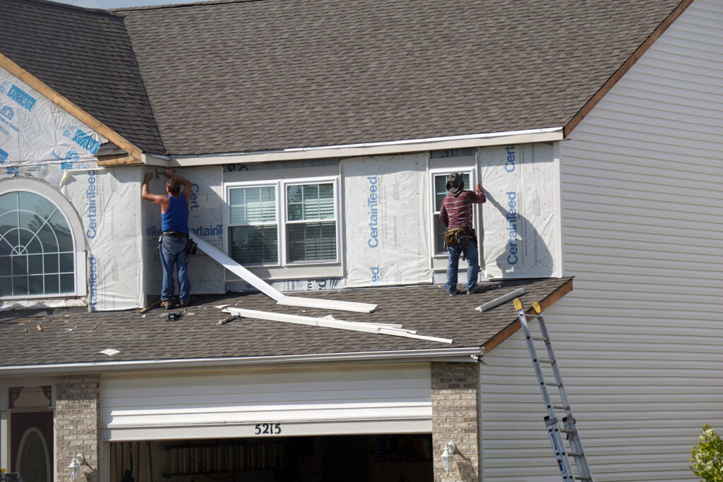 JOLIET, ILLINOIS / UNITED STATES - SEPTEMBER 7, 2016: Carpenters replace the siding on a home in the Wesmere Estates neighborhood of the Wesmere Country Club in Joliet.
